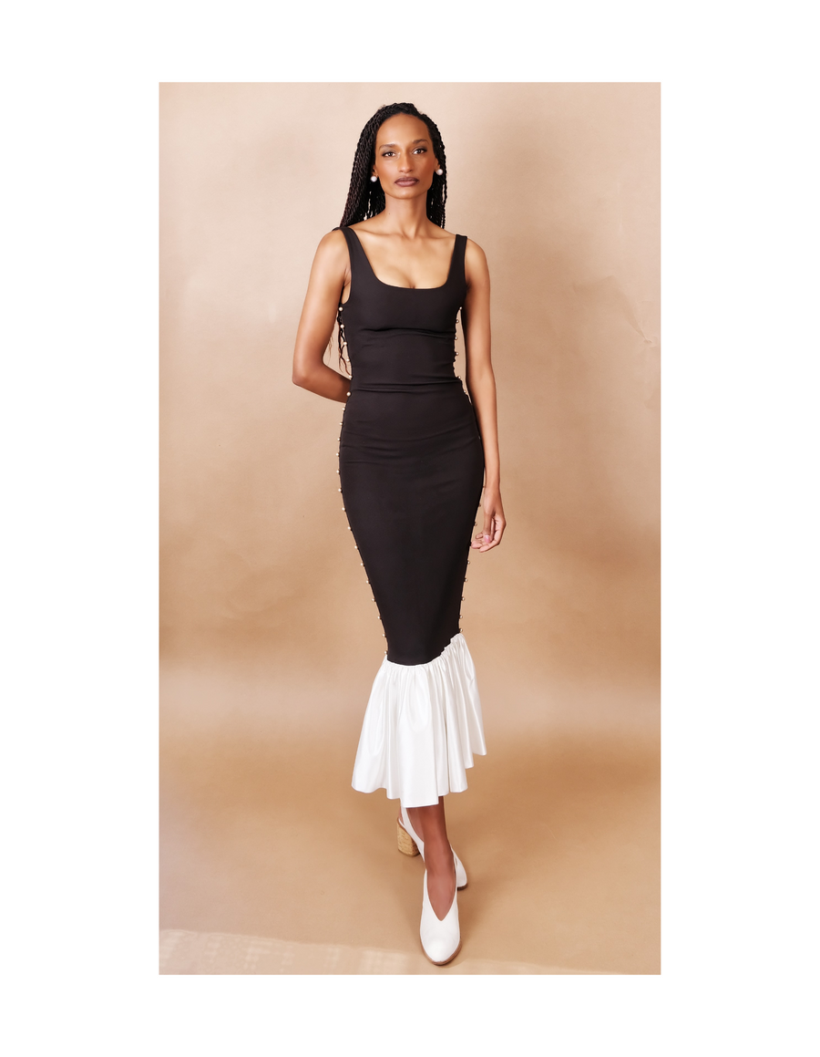Woman wearing a black sleeveless dress against a beige background. Anissa Mpungwe Atelier SS25
