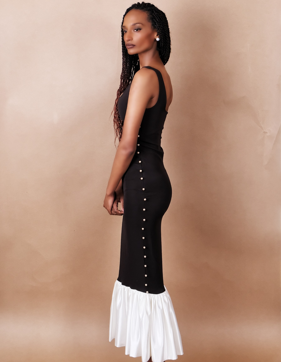 Woman wearing a black sleeveless dress against a beige background. Anissa Mpungwe Atelier SS25