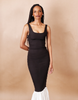 Woman wearing a black sleeveless dress against a beige background. Anissa Mpungwe Atelier SS25
