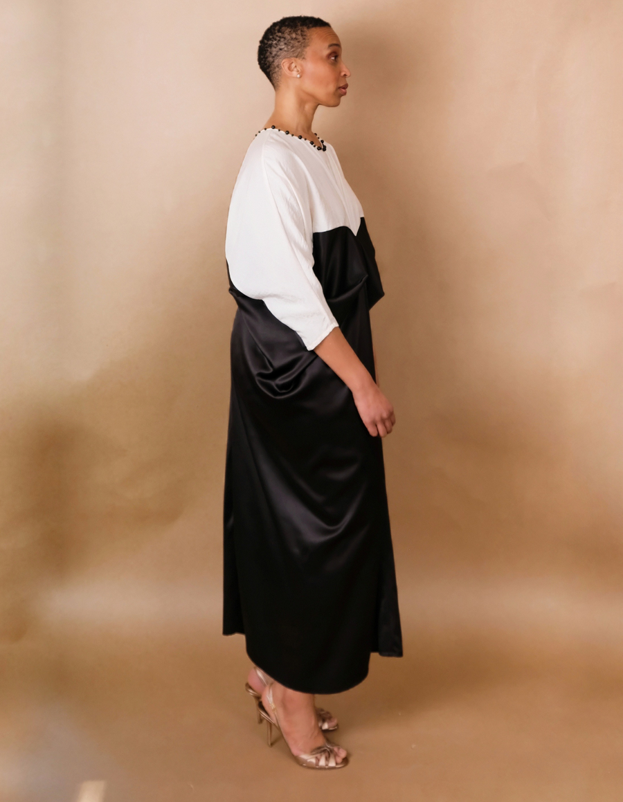Woman wearing a black and white dress against a beige background
